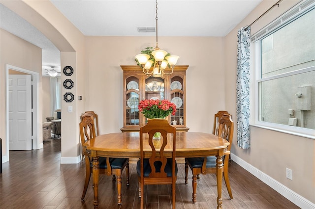 460 Tess Ct, Orlando, FL 32824 - dining room featuring a chandelier, arched walkways, dark wood-style floors, and baseboards
