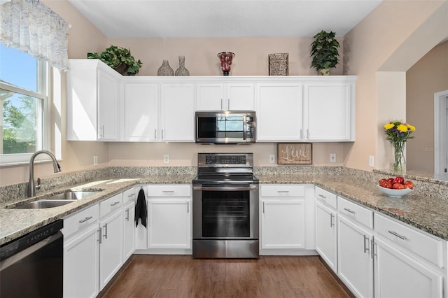 460 Tess Ct, Orlando, FL 32824 - kitchen featuring appliances with stainless steel finishes, a sink, white cabinets, dark wood finished floors, and light stone counters