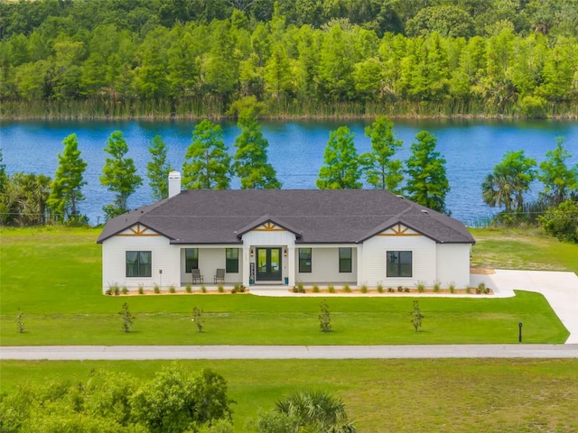 modern farmhouse style home with a water view, a front lawn, and a chimney