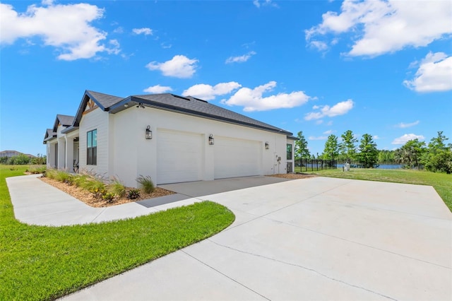 view of side of property featuring a lawn, driveway, an attached garage, and stucco siding