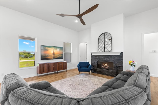living area with wood finished floors, high vaulted ceiling, a ceiling fan, baseboards, and a fireplace