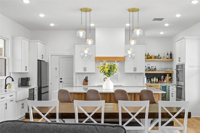 kitchen with a sink, freestanding refrigerator, a center island, light countertops, and double oven