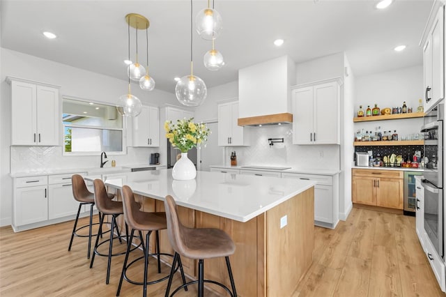 kitchen with custom range hood, light countertops, a center island, light wood finished floors, and recessed lighting