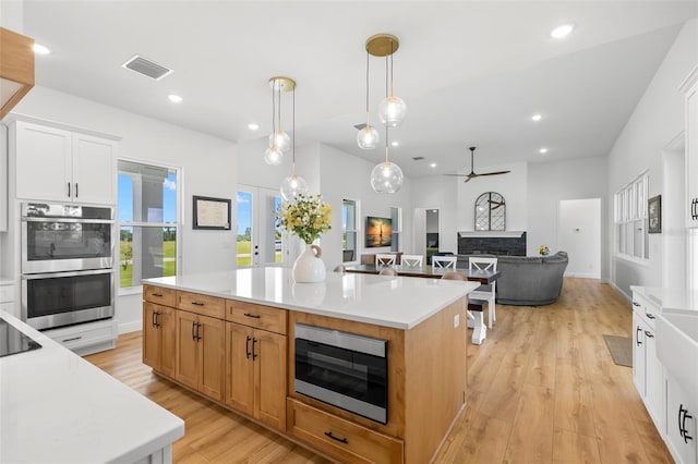 kitchen featuring stainless steel appliances, ceiling fan, light wood-style floors, light countertops, and white cabinets