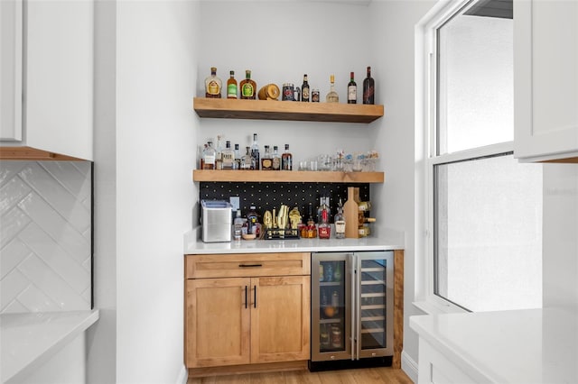 indoor dry bar featuring wine cooler, light wood-style floors, and tasteful backsplash