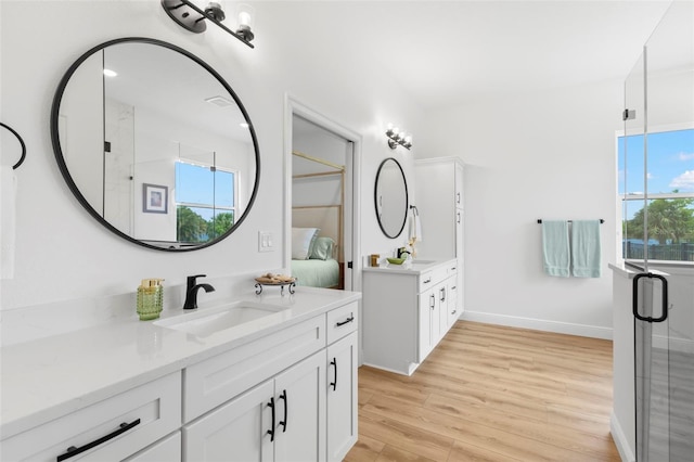 bathroom with two vanities, wood finished floors, connected bathroom, and baseboards