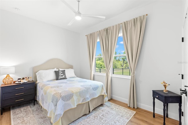 bedroom with light wood-style flooring, baseboards, and a ceiling fan