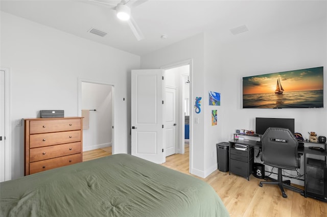 bedroom with wood finished floors, an office area, baseboards, and a ceiling fan