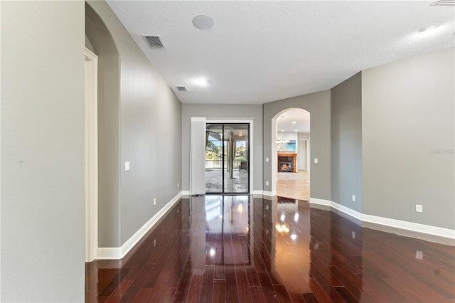 15104 Azra Dr, Odessa, FL 33556 - empty room featuring dark wood-type flooring, baseboards, arched walkways, and a glass covered fireplace