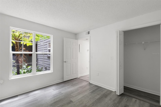 2500 Winding Creek Blvd Unit A104, Clearwater, FL 33761 - unfurnished bedroom featuring wood finished floors, a textured ceiling, a closet, and baseboards