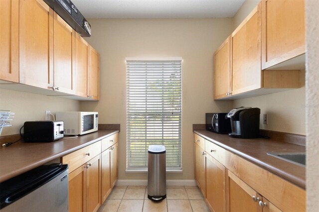 2500 Winding Creek Blvd Unit A104, Clearwater, FL 33761 - kitchen with white microwave, light tile patterned floors, black microwave, dishwasher, and baseboards