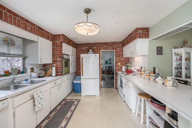 5250 12th St N, Saint Petersburg, FL 33703 - kitchen featuring white appliances, a sink, light countertops, brick wall, and white cabinets