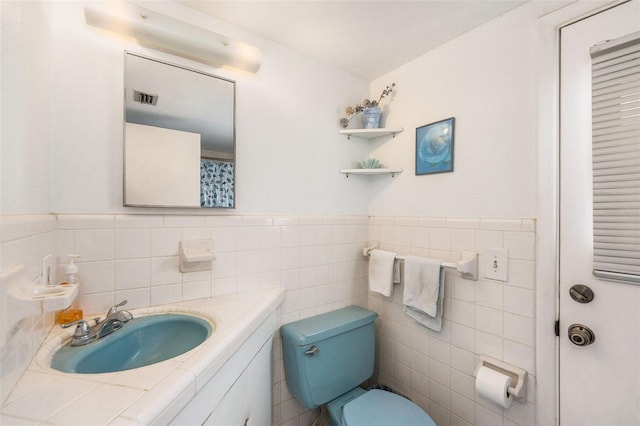 5250 12th St N, Saint Petersburg, FL 33703 - bathroom featuring toilet, vanity, tile walls, and a wainscoted wall