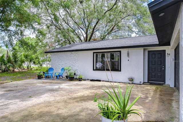 4911 Country Aire Ln, Tampa, FL 33624 - doorway to property with a patio, stucco siding, and a shingled roof