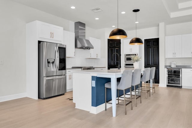 3850 Bonfire Dr, Odessa, FL 33556 - kitchen with stainless steel appliances, wine cooler, wall chimney exhaust hood, light wood-style flooring, and backsplash