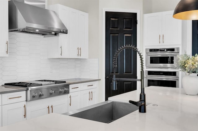 3850 Bonfire Dr, Odessa, FL 33556 - kitchen featuring wall chimney exhaust hood, stainless steel appliances, a sink, and white cabinetry