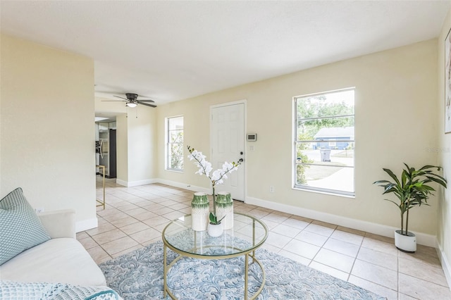 living area featuring a ceiling fan, light tile patterned floors, and baseboards