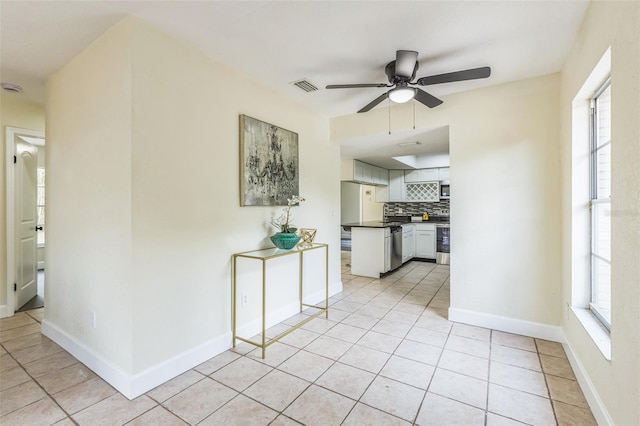 interior space featuring dark countertops, ceiling fan, backsplash, stainless steel appliances, and light tile patterned floors
