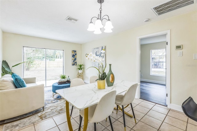 dining space featuring a chandelier, light tile patterned flooring, and baseboards