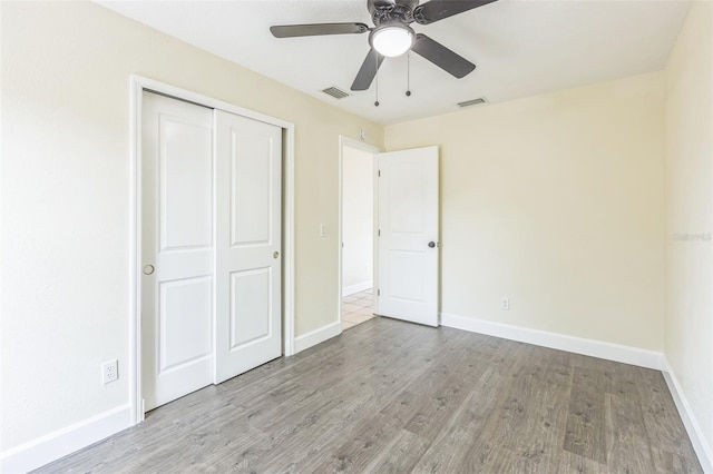 unfurnished bedroom featuring wood finished floors, baseboards, and a closet