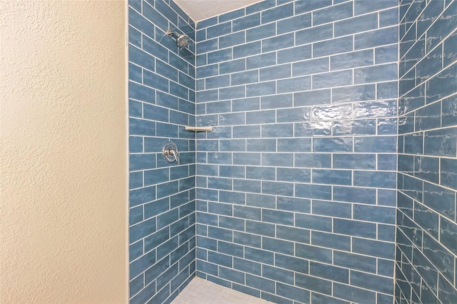 bathroom with tiled shower and a textured wall