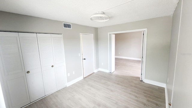 2205 Belleair Rd Unit A36, Clearwater, FL 33764 - unfurnished bedroom with light wood-style flooring, a textured ceiling, a closet, and baseboards