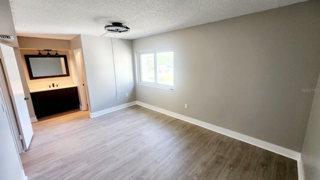 2205 Belleair Rd Unit A36, Clearwater, FL 33764 - unfurnished bedroom with light wood-style floors, a textured ceiling, baseboards, and ensuite bath
