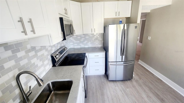 2205 Belleair Rd Unit A36, Clearwater, FL 33764 - kitchen with stainless steel appliances, a sink, light wood-style floors, white cabinets, and tasteful backsplash