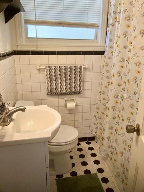 556 Virginia St, Dunedin, FL 34698 - bathroom with vanity, toilet, tile walls, and a shower with shower curtain