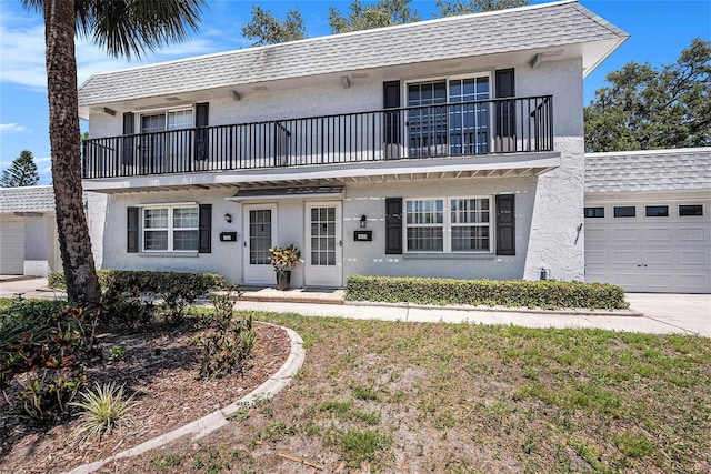 view of front facade featuring a balcony, stucco siding, and an attached garage