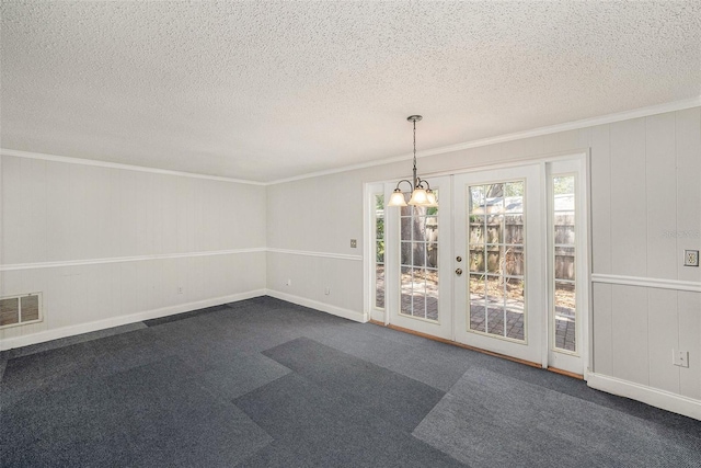 unfurnished dining area featuring a textured ceiling, crown molding, french doors, and dark carpet