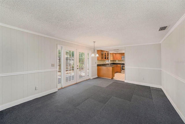 unfurnished living room with crown molding, a textured ceiling, french doors, baseboards, and dark carpet