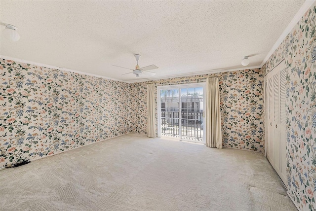 spare room with wallpapered walls, ornamental molding, a ceiling fan, a textured ceiling, and carpet flooring