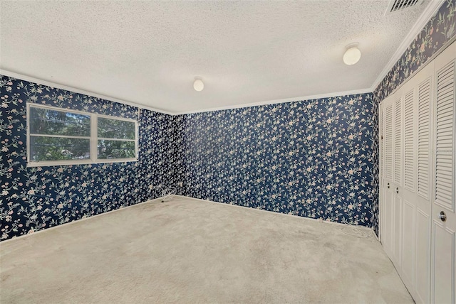unfurnished bedroom with ornamental molding, wallpapered walls, a textured ceiling, carpet flooring, and a closet