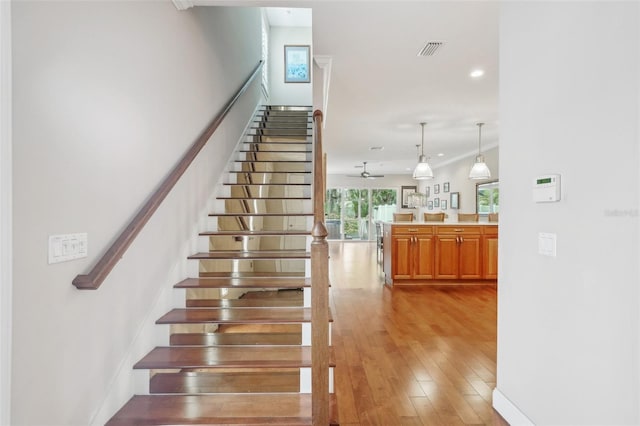 staircase with wood finished floors, crown molding, recessed lighting, and a ceiling fan