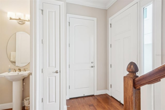 entryway featuring wood finished floors, baseboards, and crown molding