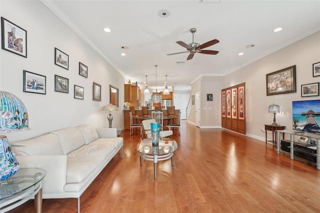 living area with ceiling fan, crown molding, recessed lighting, light wood-style floors, and baseboards
