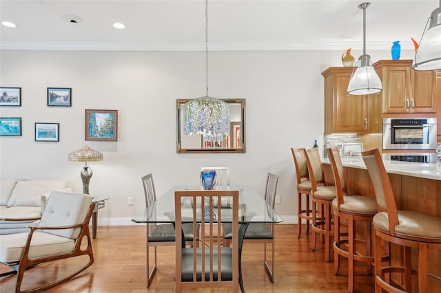 dining space featuring crown molding, light wood-style floors, baseboards, and recessed lighting