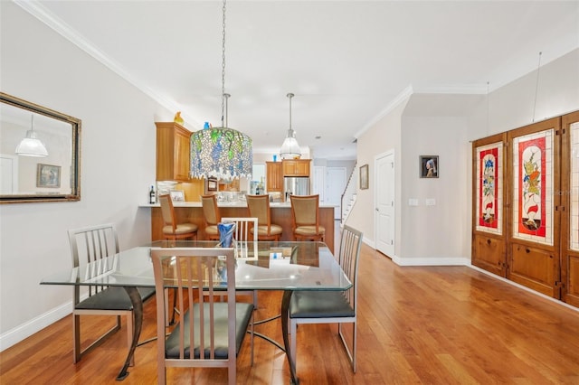 dining space with baseboards, light wood finished floors, and ornamental molding