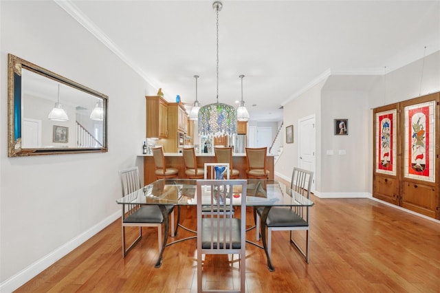 dining area with baseboards, crown molding, light wood-style floors, and stairway