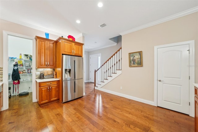 kitchen featuring stainless steel fridge, crown molding, light wood-style flooring, recessed lighting, and light countertops