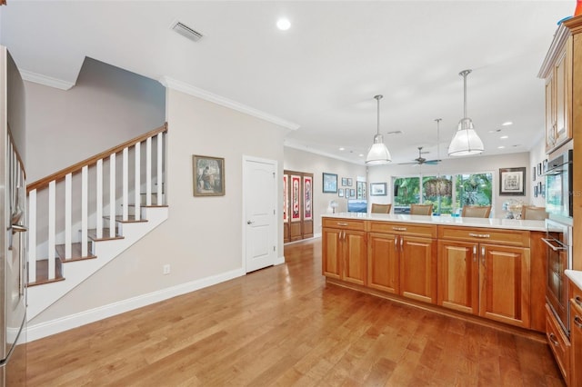kitchen with light wood finished floors, crown molding, hanging light fixtures, baseboards, and brown cabinetry