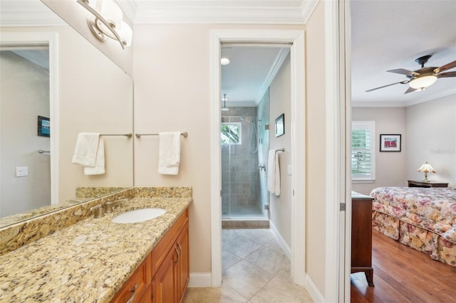 ensuite bathroom featuring healthy amount of natural light, a stall shower, ornamental molding, vanity, and baseboards