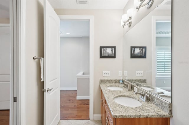 full bathroom with baseboards, double vanity, and tile patterned floors