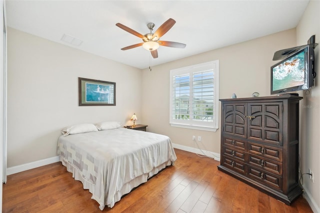 bedroom featuring baseboards, wood finished floors, and ceiling fan