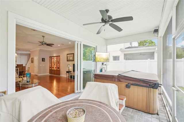 sunroom with ceiling fan, a hot tub, and plenty of natural light