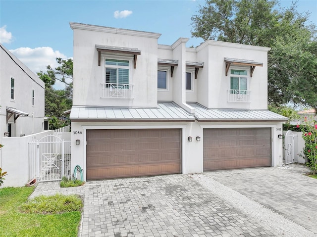 view of front of home featuring an attached garage, a gate, a standing seam roof, and decorative driveway