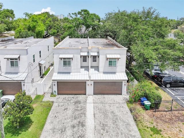 view of front of property featuring stucco siding, a garage, fence, driveway, and a gate