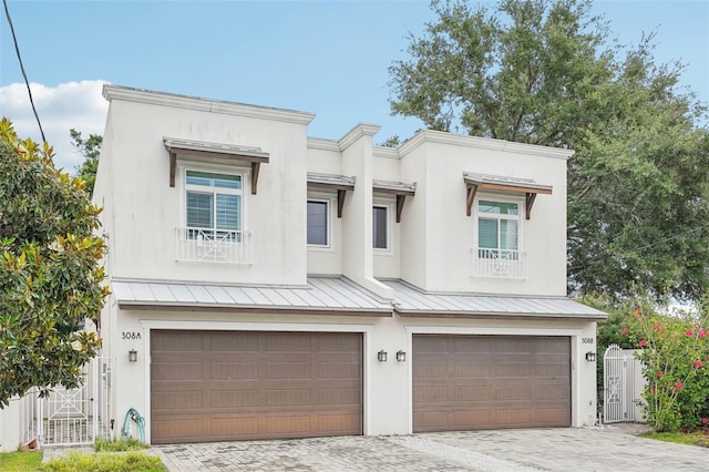view of front of house featuring a garage, decorative driveway, a standing seam roof, and stucco siding