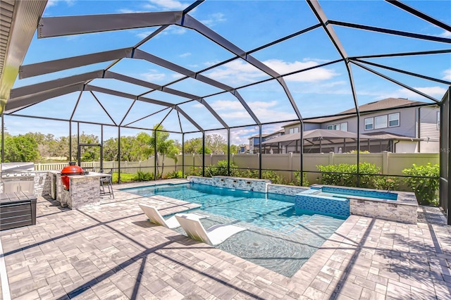 view of swimming pool featuring an outdoor kitchen, a pool with connected hot tub, a patio area, a fenced backyard, and a lanai